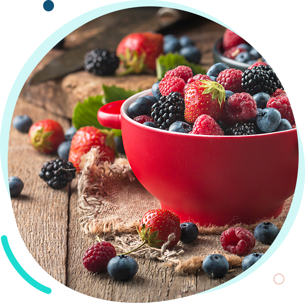 A red bowl filled with fresh mixed berries on a rustic wooden surface.