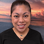 Smiling woman with ocean and sunset background.