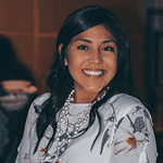 Smiling woman with long dark hair wearing a floral blouse.