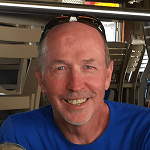 Smiling man wearing sunglasses on his head in a casual indoor setting.