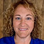 Smiling woman with curly blonde hair in a blue top.